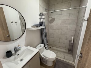 Un baño moderno con lavamanos, inodoro y ducha blancos.