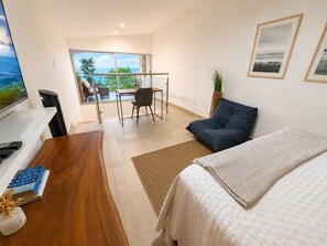 Habitación de hotel moderna con cama, escritorio, silla y vista al océano.