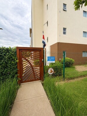 Uma entrada fechada por portão para um edifício, com uma bandeira, placa indicando acesso exclusivo e placa de proibido entrada.