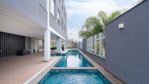 Een modern binnenzwembad met een helder uitzicht op de omliggende architectuur, waaronder een gebouw met grote ramen en een grijze gevel.