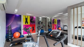 Un gimnasio con equipamiento de ejercicio, una cinta de correr y un espejo grande.