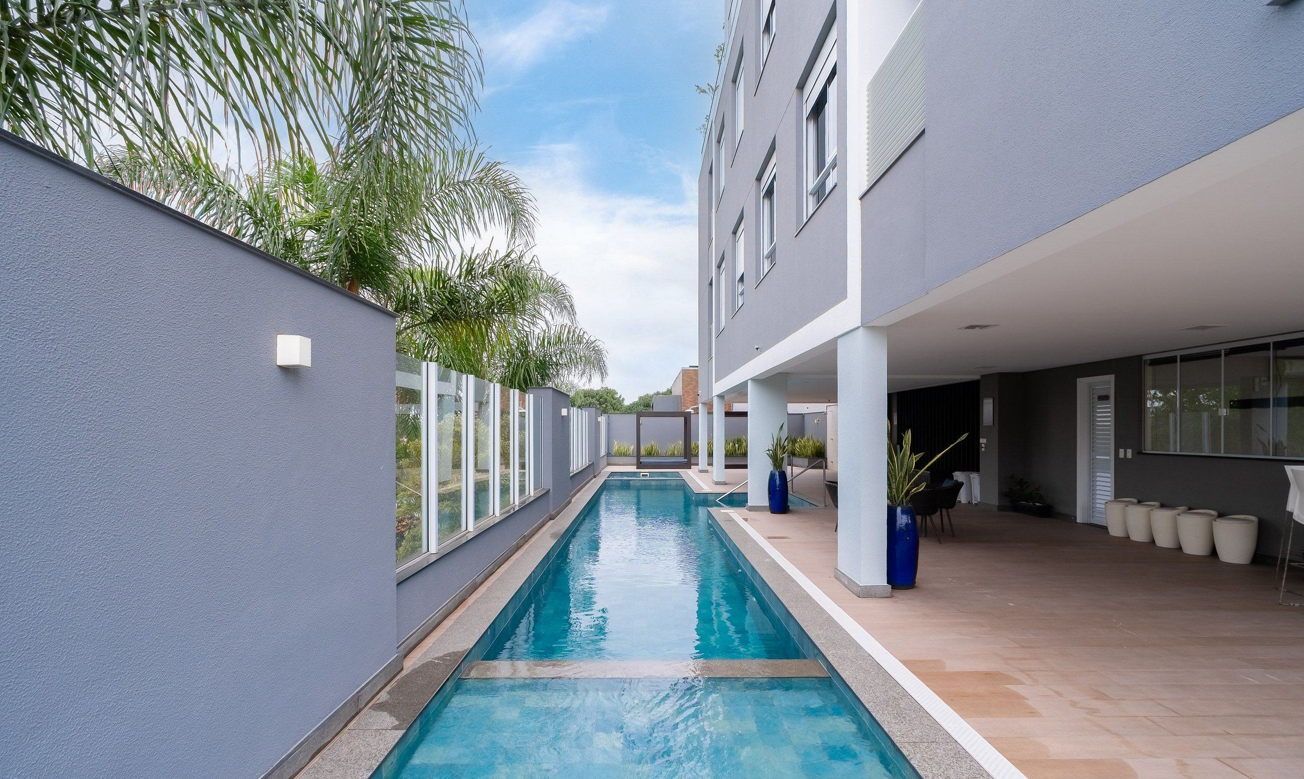 Un edificio moderno con piscina, ventanas amplias y zonas de estar al aire libre.