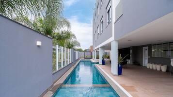 Un edificio moderno con piscina, ventanas amplias y zonas de estar al aire libre.