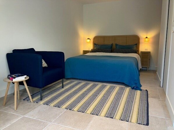 A bedroom with a bed, a blue sofa, a small table, and two bedside lamps. - Quiet studio in a green setting (Charbonnières-les-Bains)
