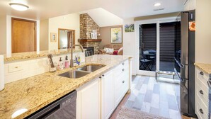A kitchen with granite countertops, a dishwasher, a stone fireplace, and a dining area with outdoor seating. - Charming 3-bedroom condo with AC in Boulder (Boulder)