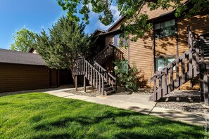 A two-story building with a wooden exterior, a covered outdoor staircase, and a well-maintained lawn.