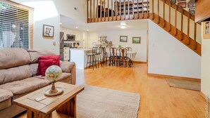 A spacious living room with a wooden staircase, a dining area, and a kitchen in the background. - Charming 3-bedroom condo with AC in Boulder (Boulder)