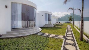Un resort moderno con edificios blancos, un césped cuidado y una vista despejada de las montañas al fondo.