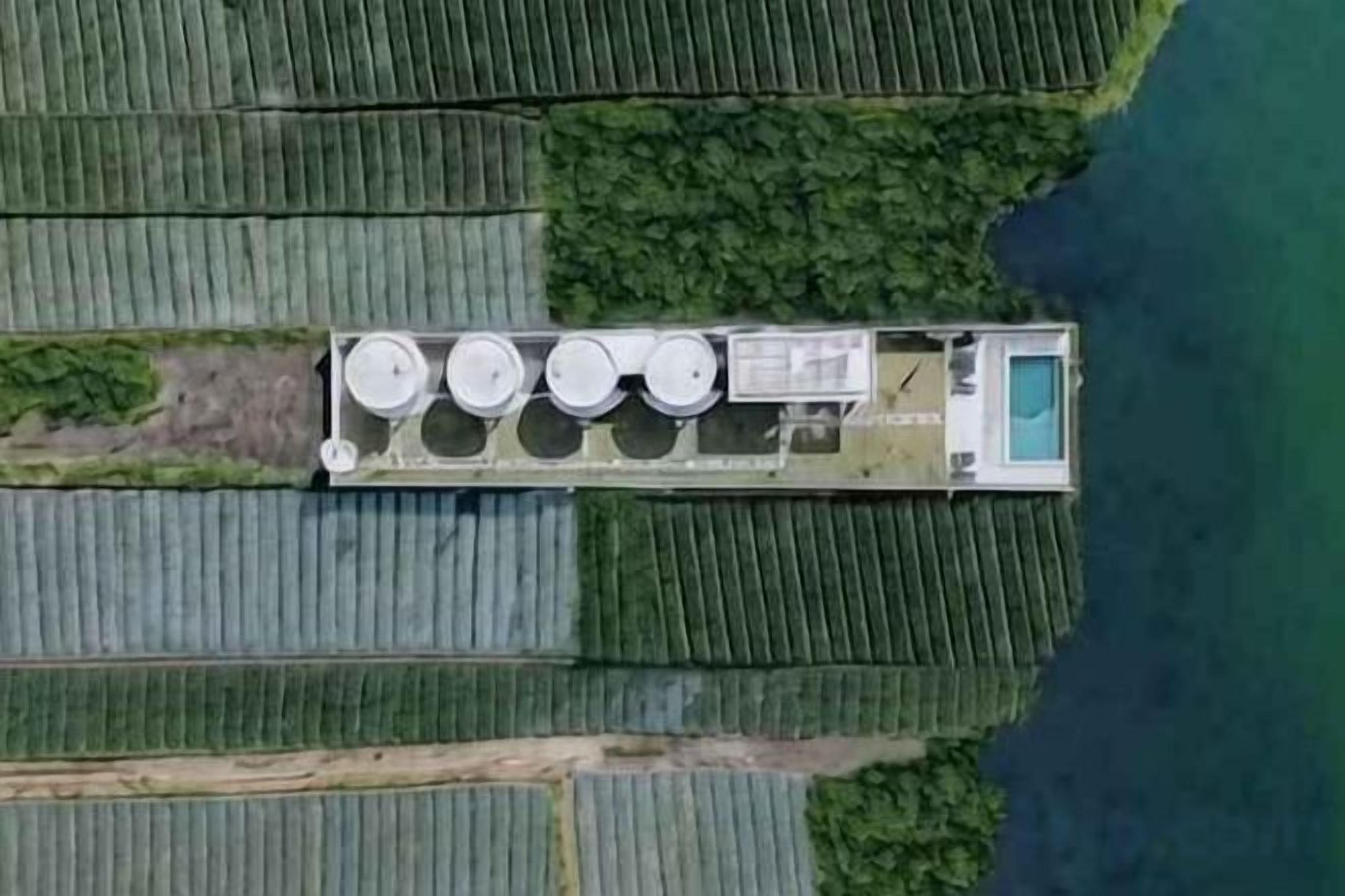 Vista aérea de una propiedad con un edificio alargado, varias estructuras cilíndricas y una piscina.