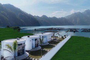 A modern hotel with circular structures, a waterfront view, and a mountainous backdrop. - Intan Lake View Kintamani (Bali)