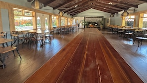A spacious dining area with wooden tables and chairs, large windows, and a high ceiling with exposed beams. - Ecoblue Resort Avaré (Avaré)