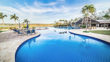 Een buitenzwembad, parasols bij het zwembad en ligstoelen