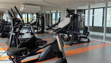 Un gimnasio con varias máquinas de ejercicio, ventanas amplias y un diseño moderno y limpio.