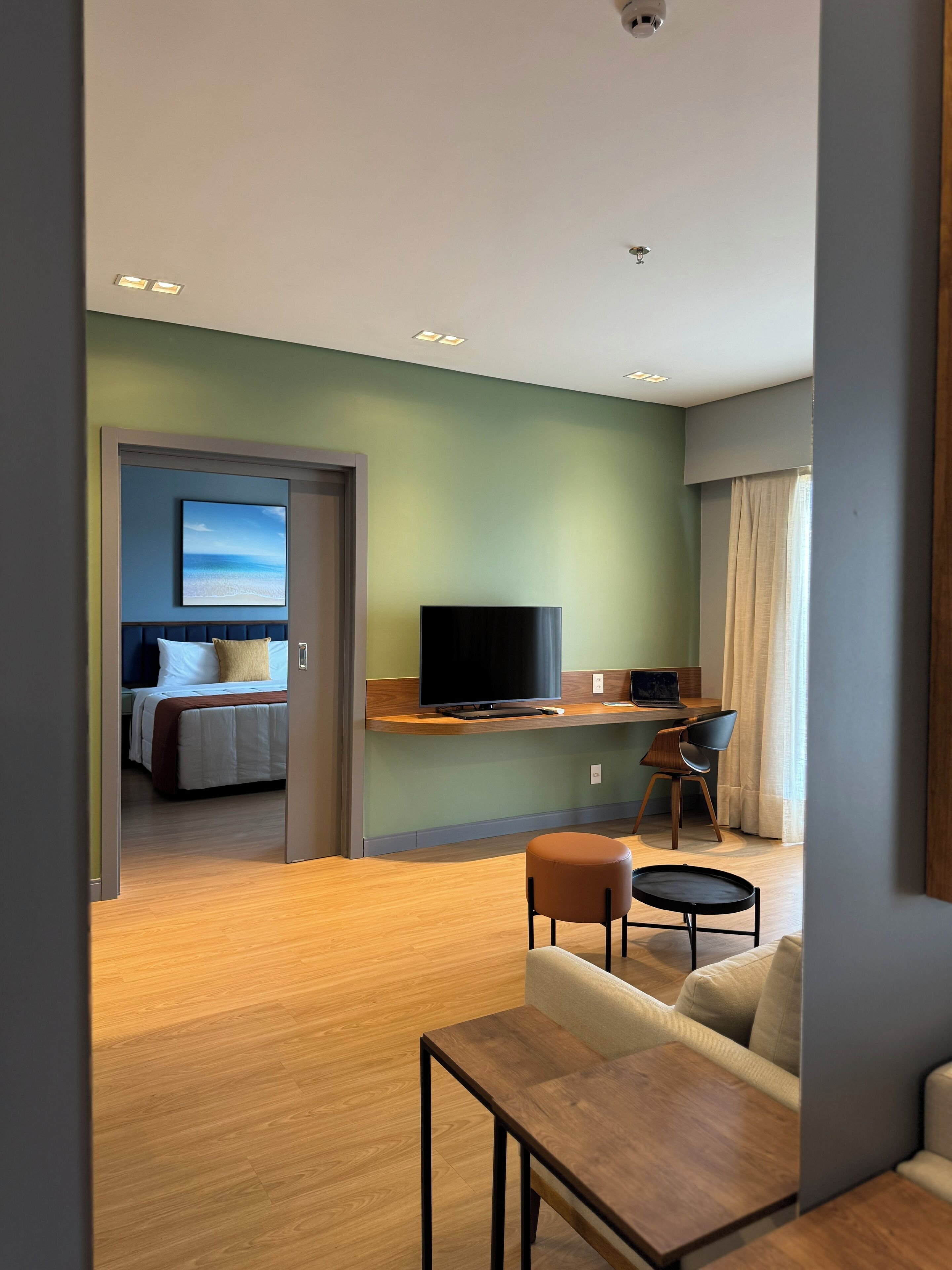 Ein Hotelzimmer mit Bett, Fernseher, Schreibtisch und Sitzecke.