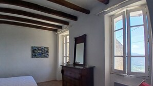 Un dormitorio con cama, cómoda, espejo y ventana con vistas.