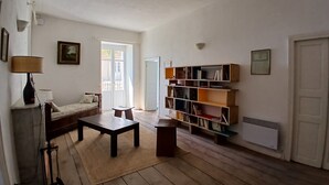 Una sala de estar con un sofá, una mesa de centro, una estantería y un radiador.
