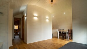 A compact, modern interior with a wooden floor, a dining area with a table and chairs, and a curved ceiling.