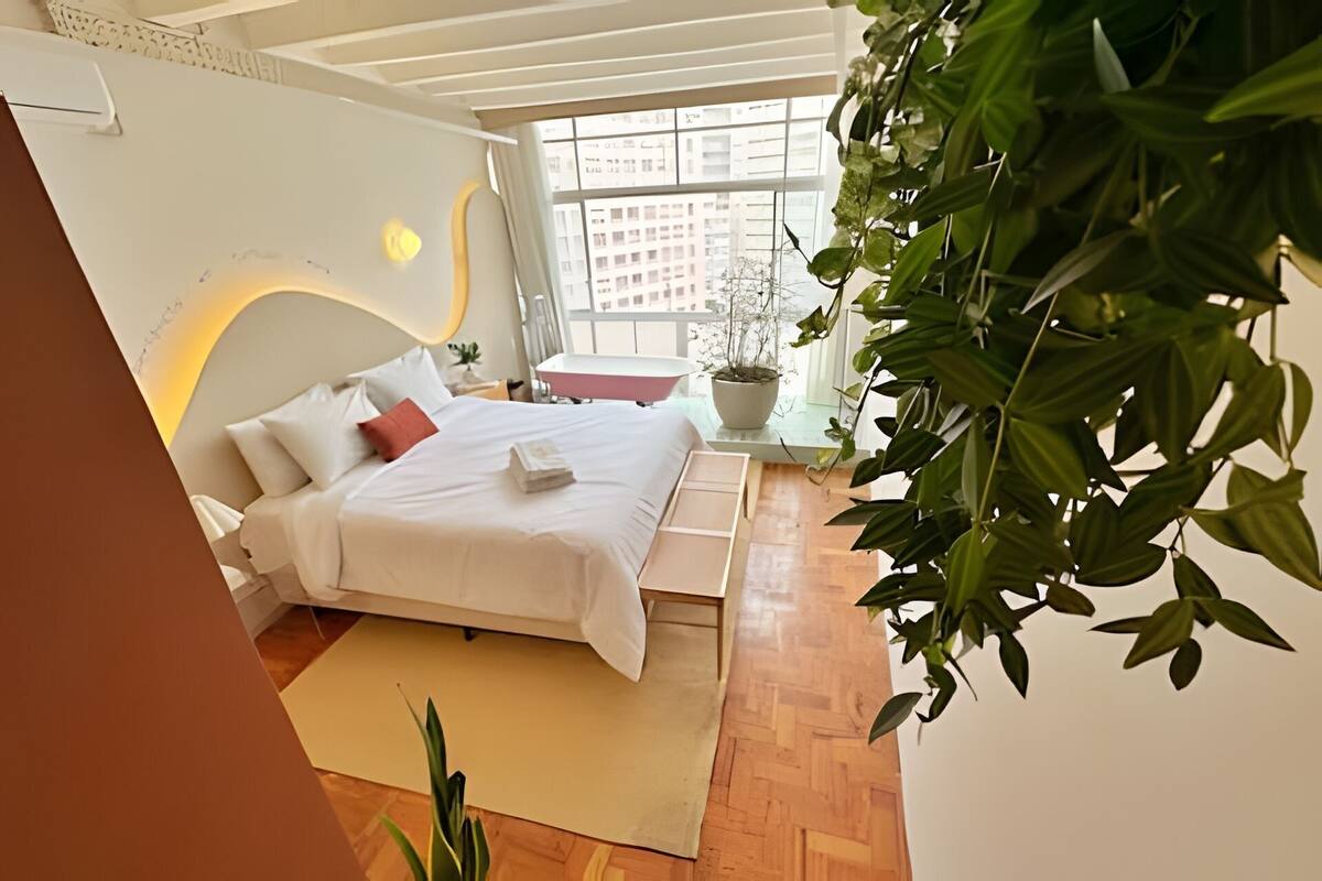 Une chambre à coucher moderne avec un lit, une table de chevet et une plante en pot.