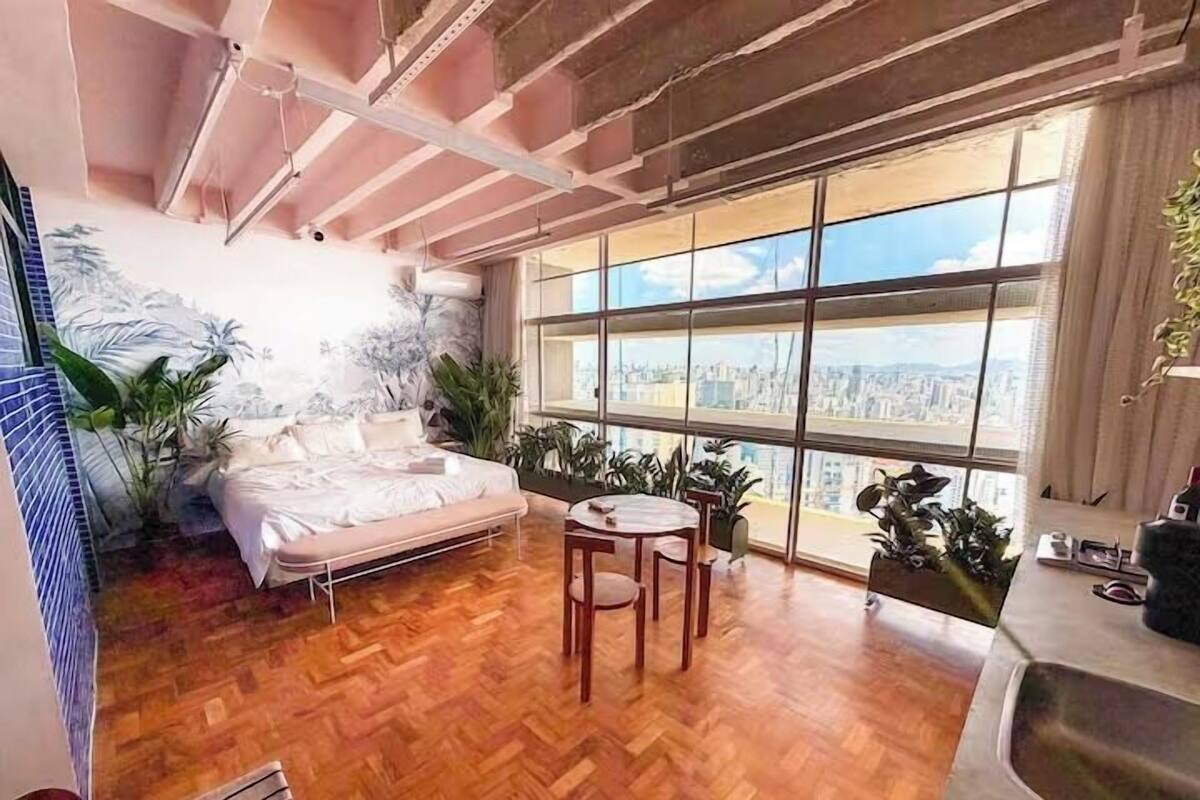 Une chambre avec un lit, une petite table, une fenêtre donnant sur la ville et un coin cuisine.