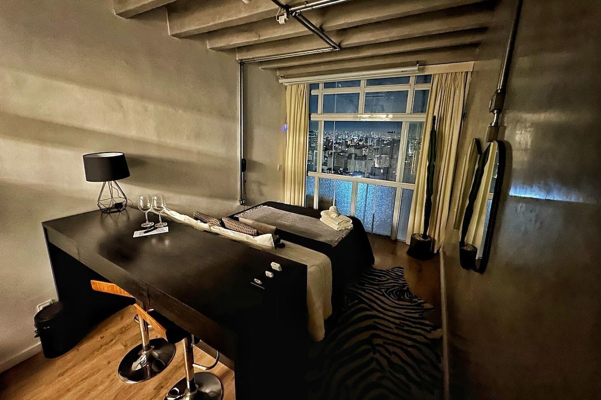 Une chambre moderne avec vue sur la ville, un bureau avec une lampe et un tapis à motifs zébrés.