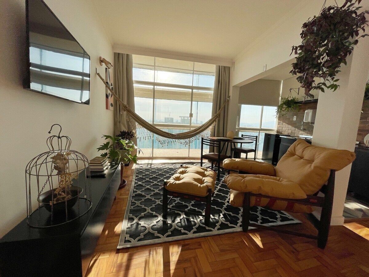 Ein Wohnzimmer mit großem Fenster, einer Hängematte, einer Couch und einem Essbereich.