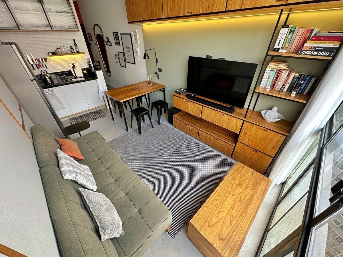 Ein gemütlicher Wohnbereich mit Sofa, Esstisch, Fernseher und Bücherregal.