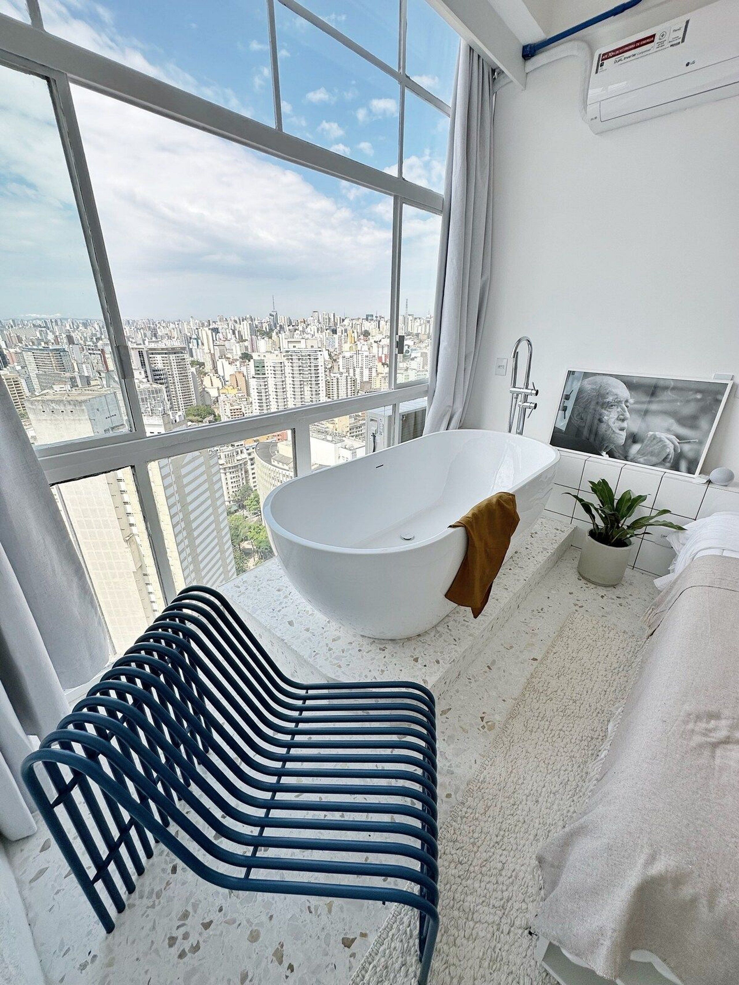 Ein modernes Badezimmer mit einer großen Badewanne, Blick auf die Stadt und einem außergewöhnlichen Stuhldesign.