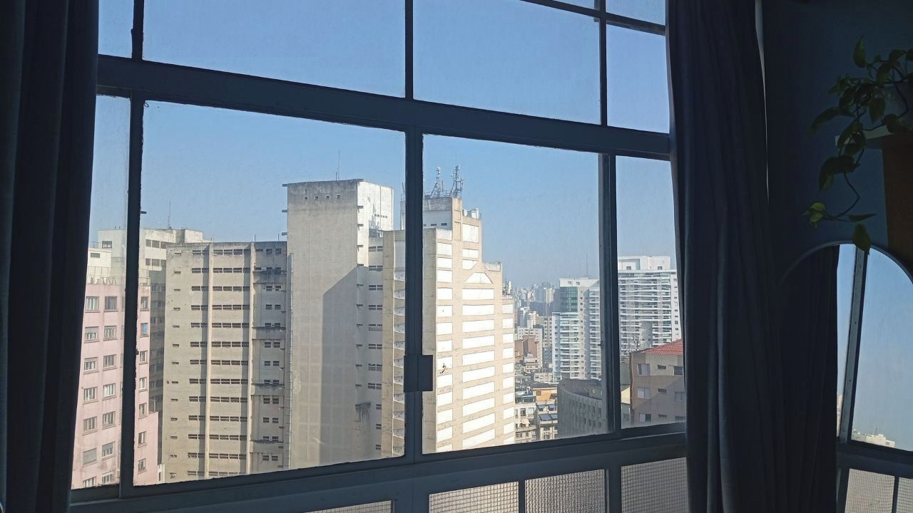 A view through a window with a grid pattern, overlooking a cityscape with multiple high-rise buildings.