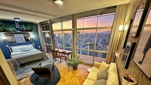 A modern living room with a sofa, a coffee table, and a dining area with chairs. - Vem pro Copan (São Paulo)