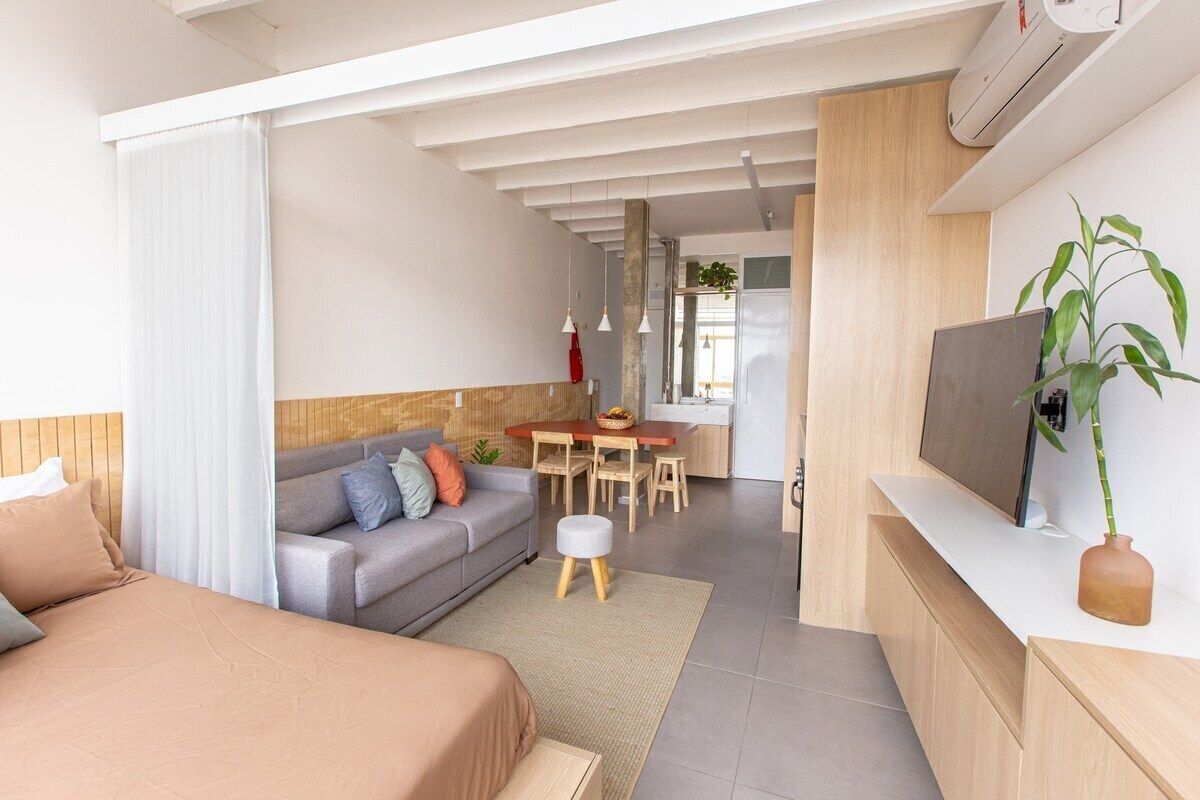 Ein moderner, gut beleuchteter Raum mit einem Bett, einer Couch, einem Essbereich und einem Fernseher.