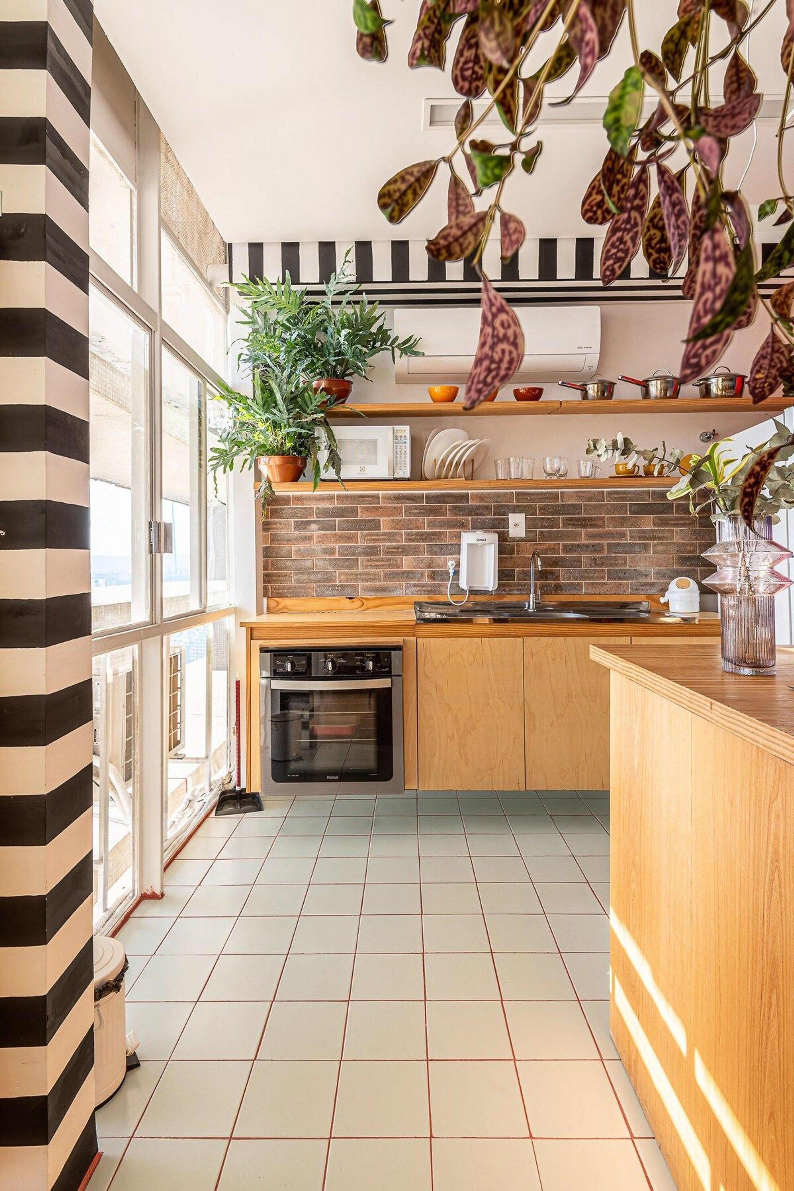 A modern kitchen with a brick backsplash, wooden cabinets, and a large window.