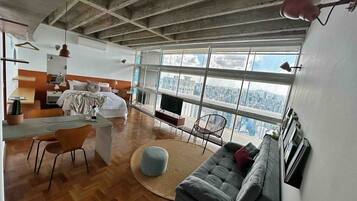 A modern living room with a sofa, a dining area with chairs, a small table, and a television.
