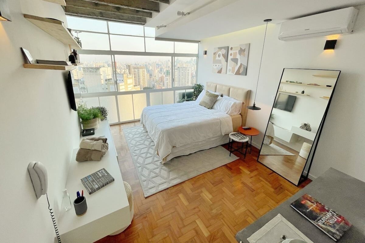 Une chambre à coucher moderne avec un grand lit, un bureau et un miroir.