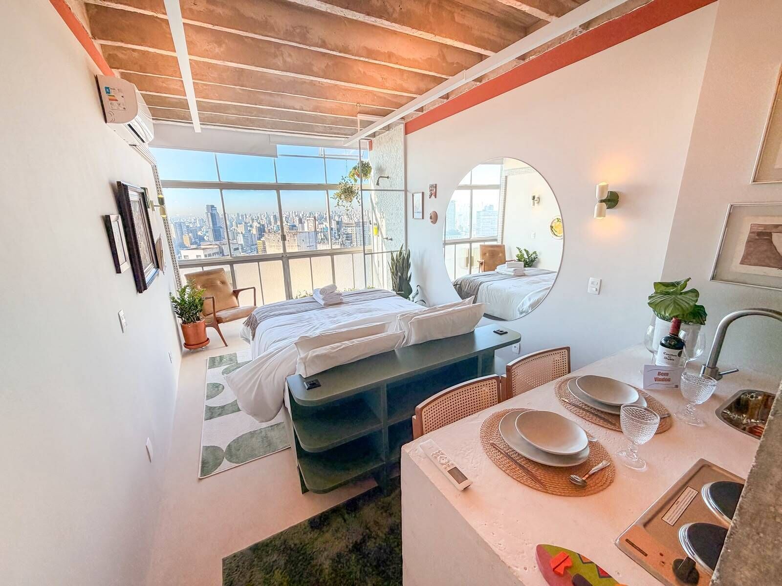 Una habitación de hotel moderna con vista a la ciudad, una cama, un área de comedor y un baño.