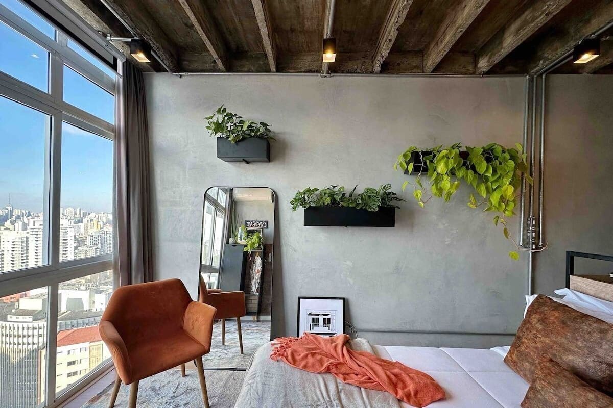 Une chambre moderne avec une grande fenêtre, un lit, une chaise et deux jardinières fixées au mur.