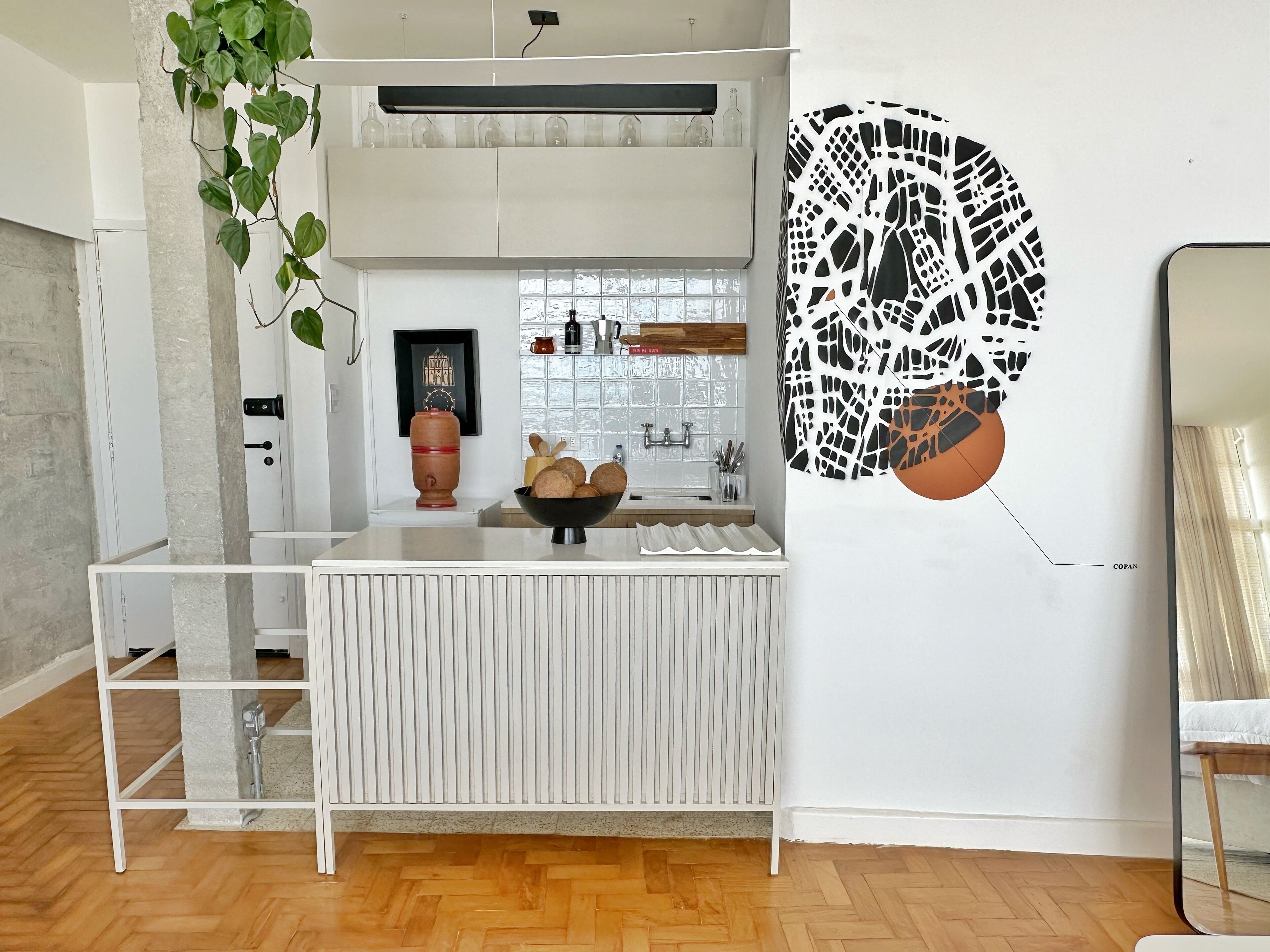 A modern kitchen with a white countertop, a bowl of bread, and a decorative wall piece.