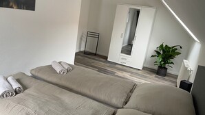A modern bedroom with two beds, a large mirror, a potted plant, and a skylight. - Modern vacation apartment with style & comfort (Ovelgönne)