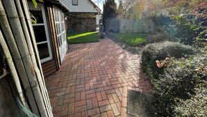 A brick pathway leading to a white house with a small window and a door. - Modern vacation apartment with style & comfort (Ovelgönne)