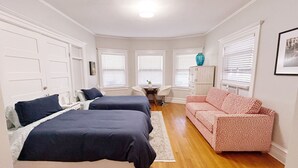 Une chambre avec deux lits, un bureau, une chaise, un canapé et un placard.