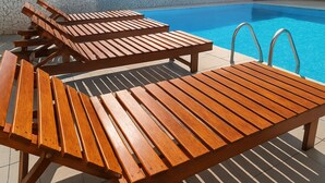Zona de piscina amb gandules de fusta i una piscina.