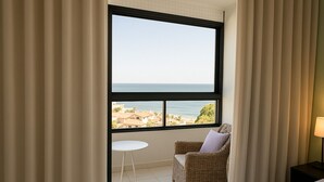 Habitació amb una finestra gran, una cadira de vimbles, un taulell petit i una làmpada.