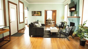Uma sala de estar com sofá, mesa de centro, cadeiras, lareira e um espaço de jantar com mesa e cadeiras.