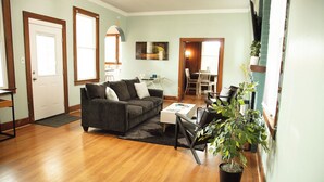 Uma sala de estar com sofá, mesa de centro e um espaço de refeições com cadeiras e mesa.
