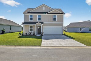 A two-story house with a garage, a front porch, and a well-maintained lawn. - Family Fun w/Game Rm, WFH Office: 8 Min to Beach (Ocean Isle Beach)