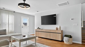A modern living room with a sofa, coffee table, and a TV mounted on the wall. - Family Fun w/Game Rm, WFH Office: 8 Min to Beach (Ocean Isle Beach)