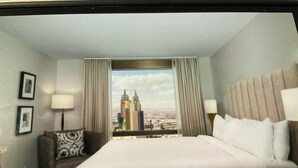 A hotel room with a large bed, a nightstand, a chair, a window with a cityscape view, and a framed picture on the wall. - Marriott Grand Chateau Charming 2-bedroom Villa-Las Vegas. (Las Vegas)