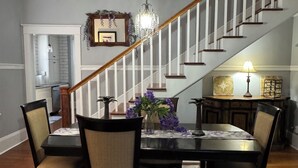 A dining area with a chandelier, a staircase, and a kitchen in the background. - The Wisteria House invites you to relax and enjoy! (Shelby)