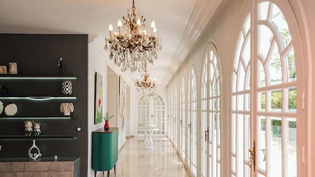 A spacious hallway with a chandelier, a teal console table, and a marble cabinet. - Palais Elya (Rabat)