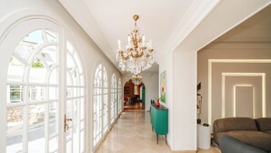A spacious hallway with a chandelier, a teal console table, and a brown sofa. - Palais Elya (Rabat)