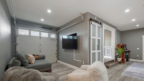 Un salon moderne avec un canapé gris, un grand fauteuil gris et un téléviseur à écran plat fixé au mur.